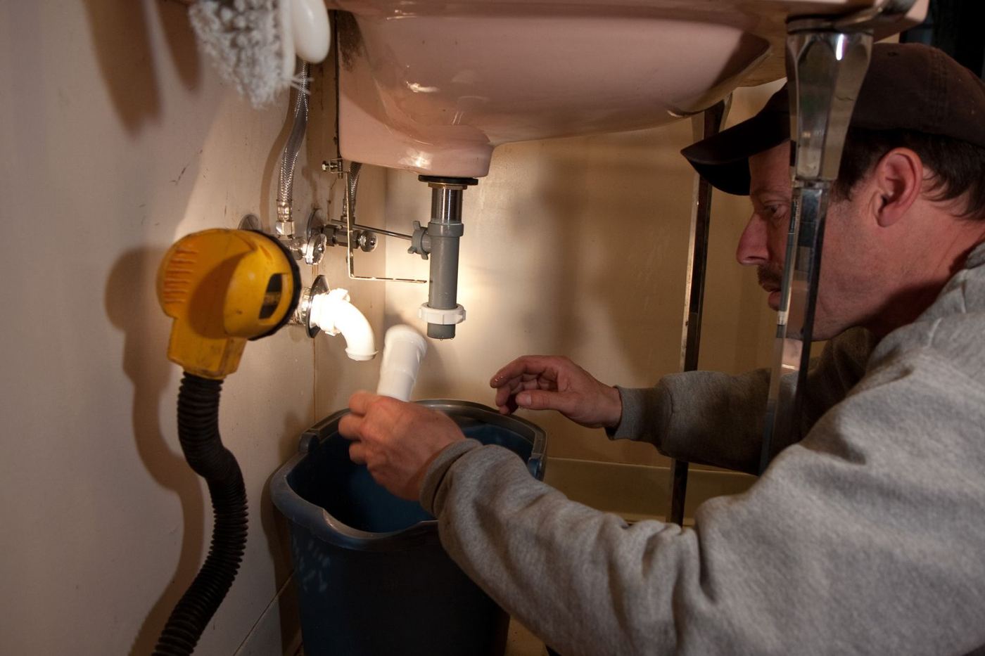 Plumber repairing pipes under a sink