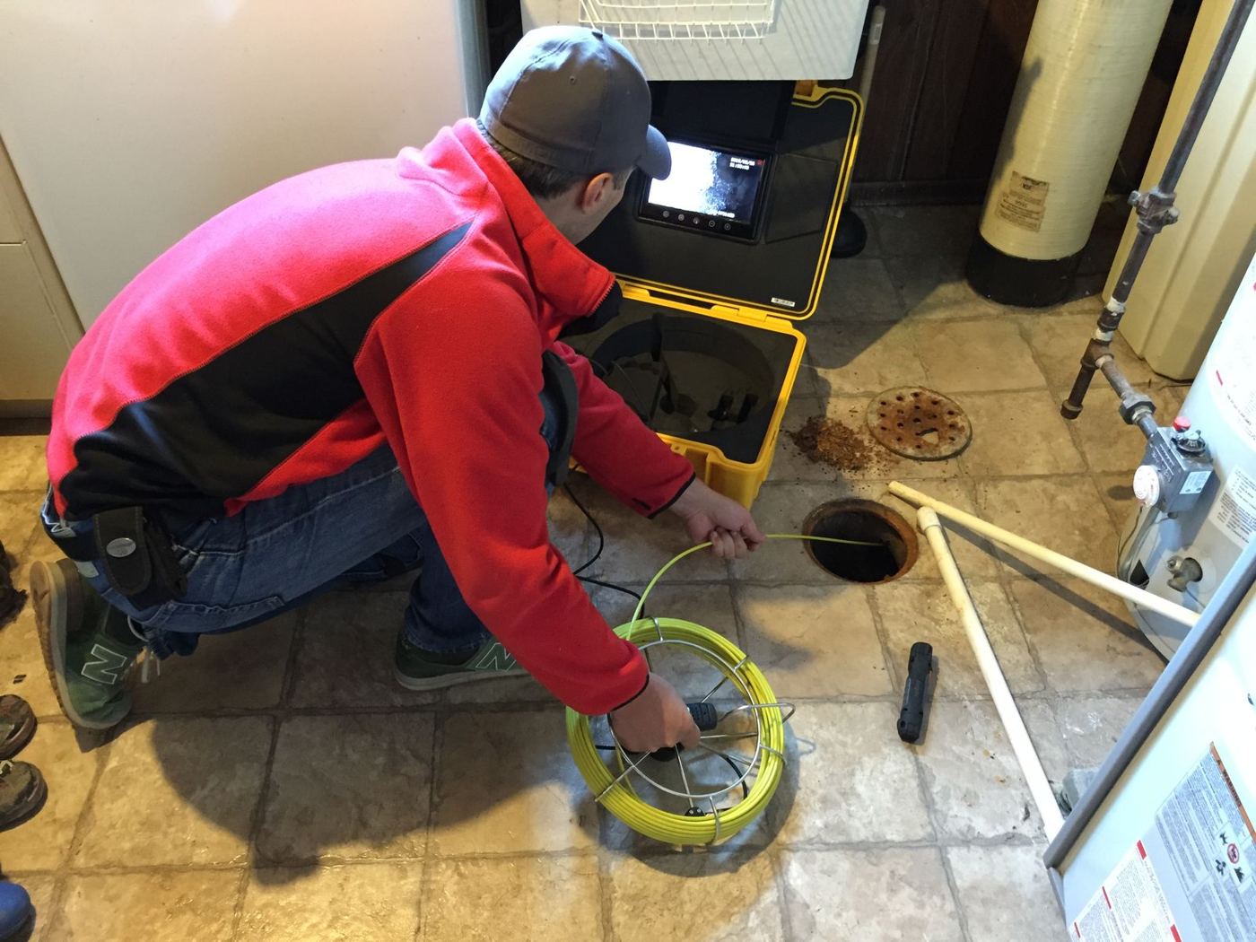 Technician feeding a drain inspection camera into a floor drain